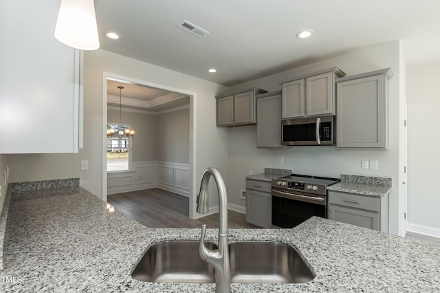 kitchen featuring light stone counters, stainless steel appliances, sink, and pendant lighting