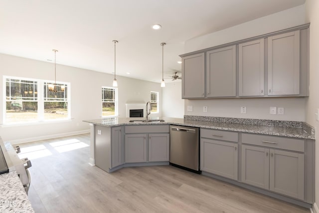 kitchen with decorative light fixtures, a peninsula, gray cabinetry, stainless steel dishwasher, and a sink