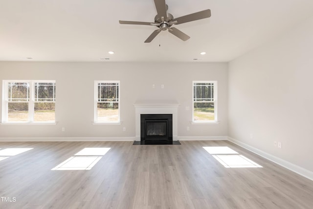 unfurnished living room featuring ceiling fan, a healthy amount of sunlight, and light wood-type flooring