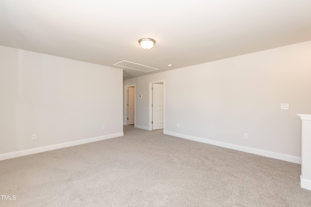 unfurnished room with attic access, baseboards, and light colored carpet