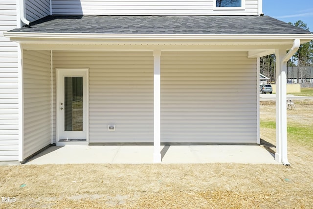 exterior space with roof with shingles and a patio