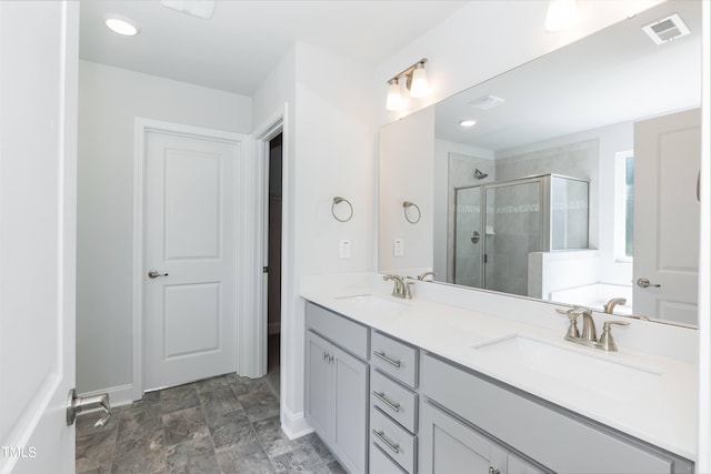 full bath with visible vents, a sink, a shower stall, and double vanity