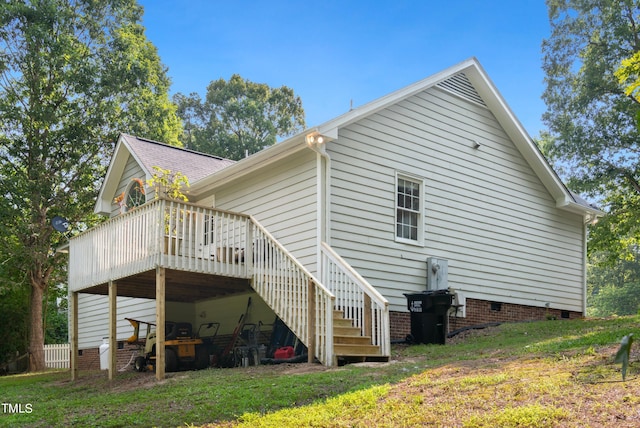 back of property with a wooden deck and a lawn