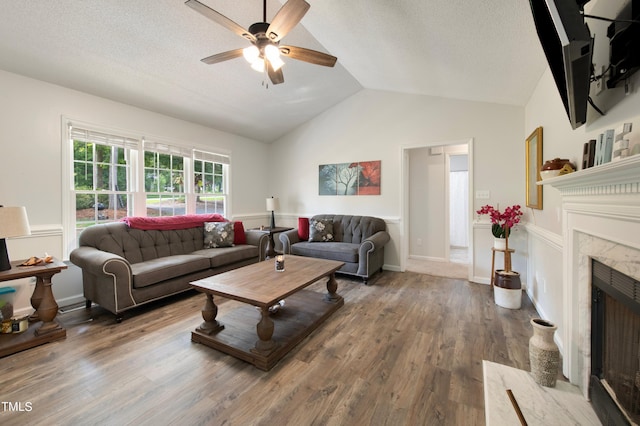 living room with hardwood / wood-style flooring, a fireplace, vaulted ceiling, and a textured ceiling