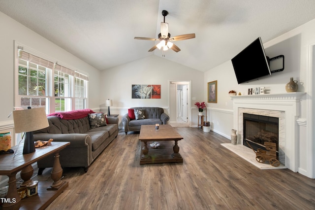 living room featuring dark hardwood / wood-style floors, a fireplace, lofted ceiling, ceiling fan, and a textured ceiling