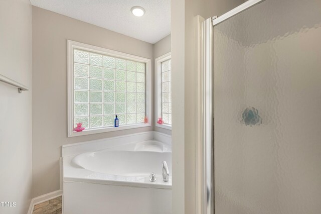 bathroom featuring independent shower and bath and a textured ceiling