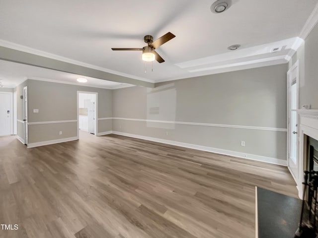 unfurnished living room featuring wood finished floors, a ceiling fan, baseboards, and ornamental molding