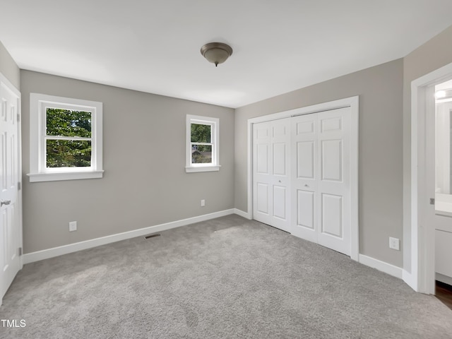 unfurnished bedroom with baseboards, carpet floors, visible vents, and a closet