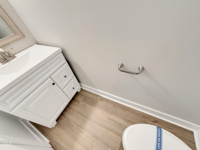 bathroom with baseboards, wood finished floors, and vanity