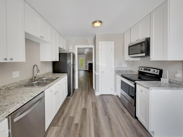 kitchen featuring white cabinets, light wood-style floors, stainless steel appliances, and a sink