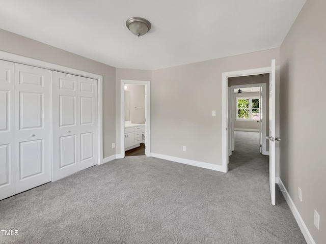 unfurnished bedroom featuring ensuite bath, carpet floors, a closet, and baseboards