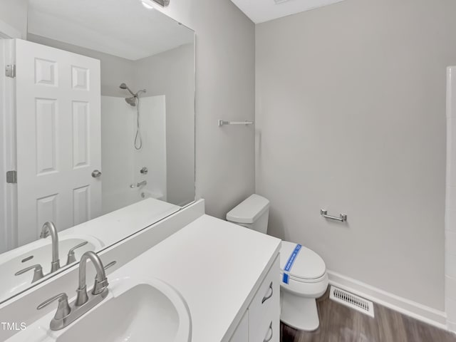 bathroom with toilet, visible vents, walk in shower, wood finished floors, and vanity