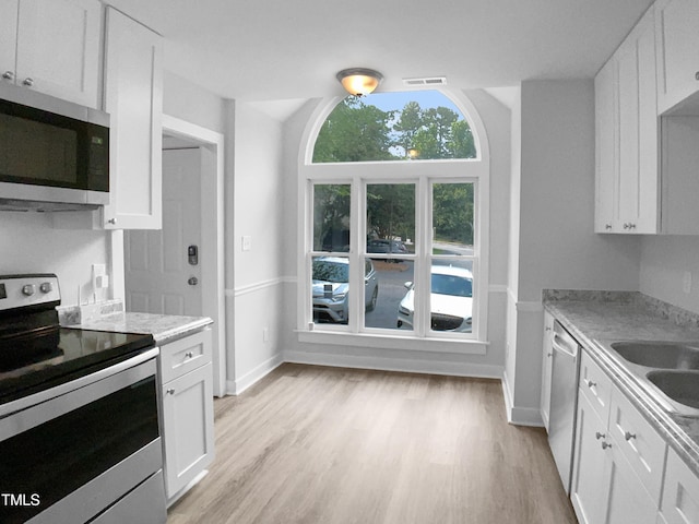 1432 Quarter Pt, Raleigh, NC 27615 - kitchen with appliances with stainless steel finishes, light countertops, light wood-style flooring, and white cabinets