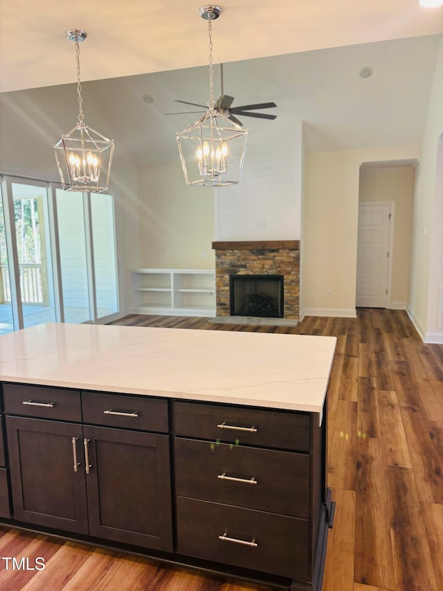 kitchen with wood-type flooring, dark brown cabinets, a fireplace, and vaulted ceiling