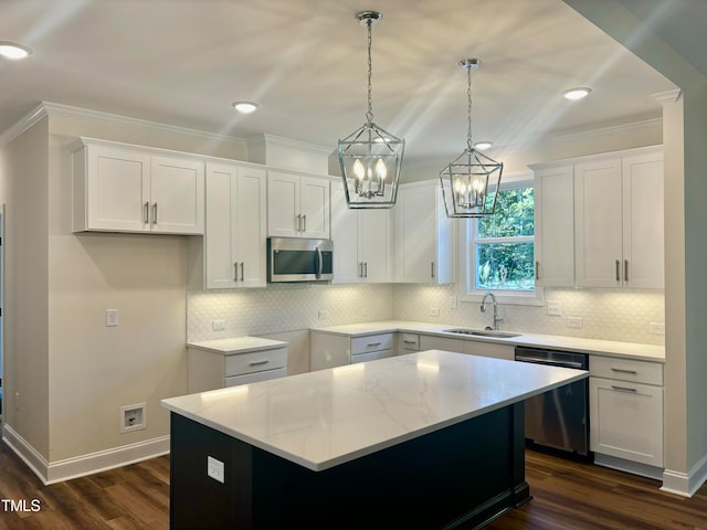 kitchen with appliances with stainless steel finishes, white cabinets, sink, and a kitchen island