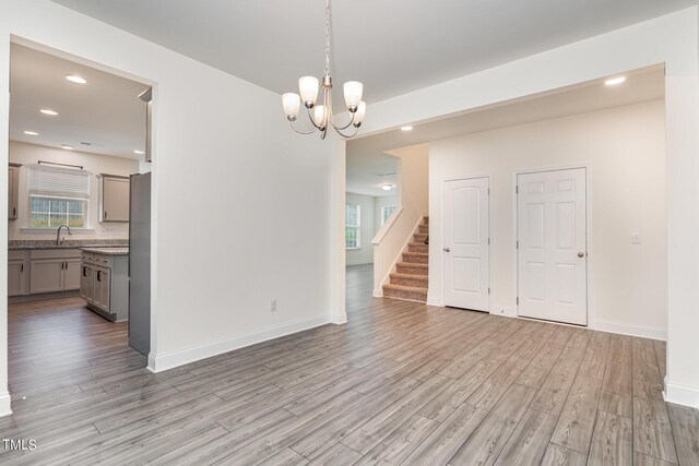 spare room featuring sink, light wood-type flooring, and a notable chandelier