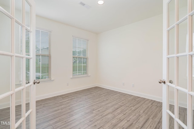 spare room with french doors and light hardwood / wood-style flooring