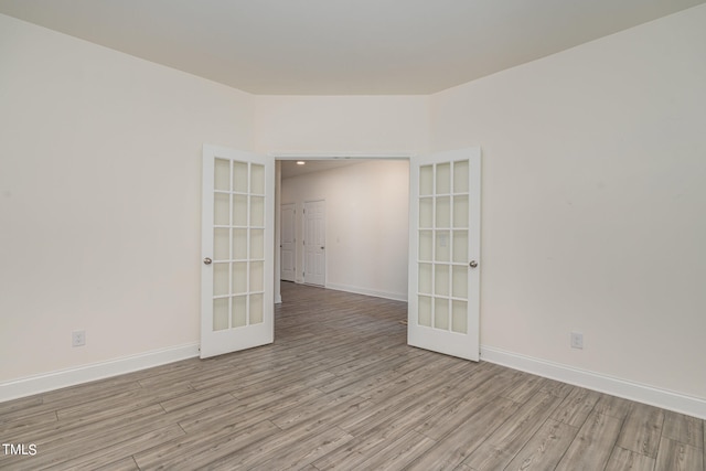 spare room featuring light hardwood / wood-style floors and french doors