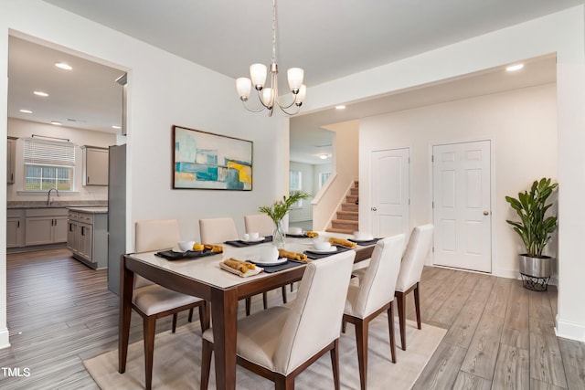 dining space with light wood-type flooring, sink, and a notable chandelier