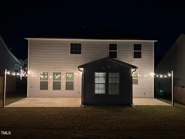 back house at twilight featuring a patio