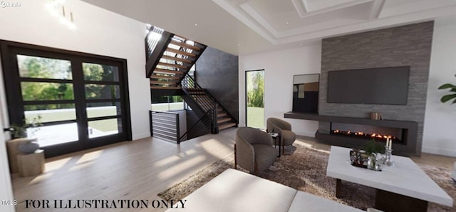 living room with wood finished floors, a warm lit fireplace, and stairs