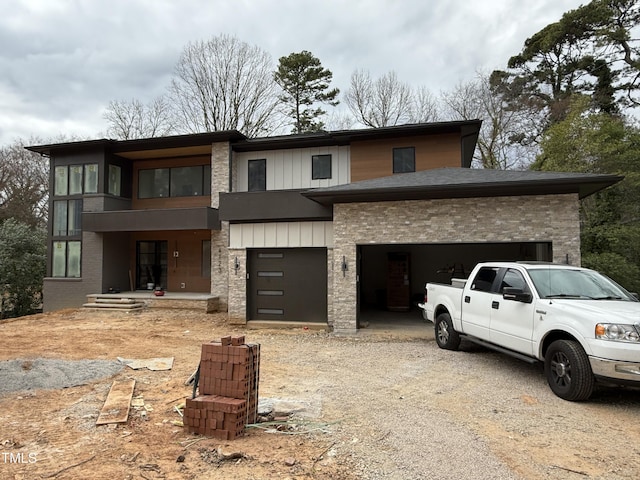 view of front of home featuring a garage, roof with shingles, gravel driveway, board and batten siding, and brick siding