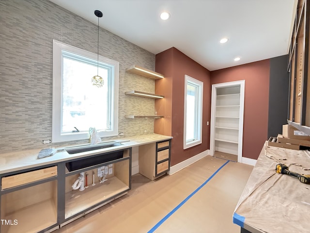 kitchen with tasteful backsplash, recessed lighting, light countertops, a sink, and baseboards