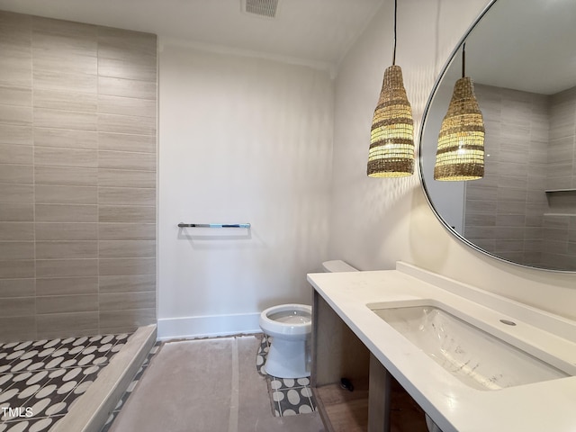 bathroom with baseboards, visible vents, toilet, a tile shower, and vanity