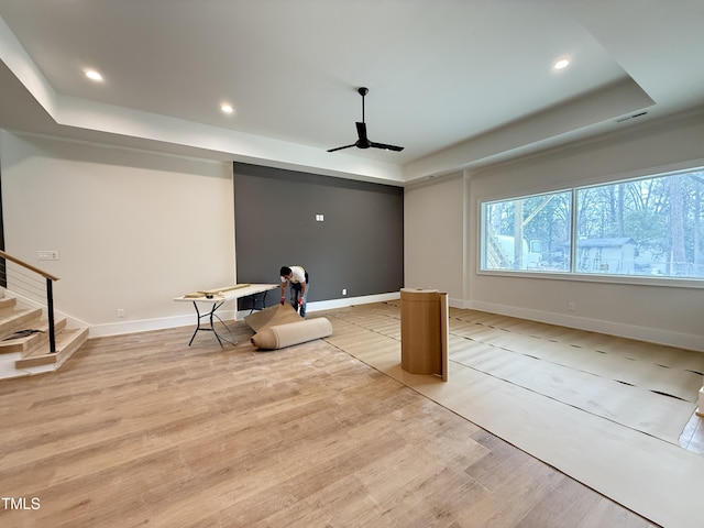 unfurnished room featuring light wood finished floors, baseboards, a raised ceiling, stairway, and recessed lighting