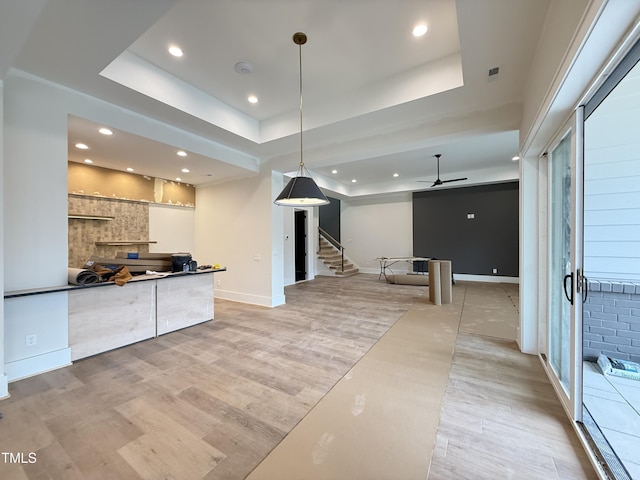 kitchen featuring light wood finished floors, baseboards, a tray ceiling, and recessed lighting