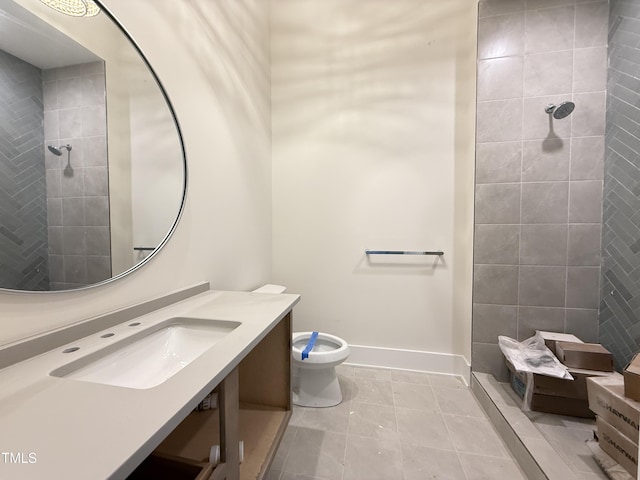 bathroom with baseboards, toilet, tile patterned flooring, a tile shower, and vanity