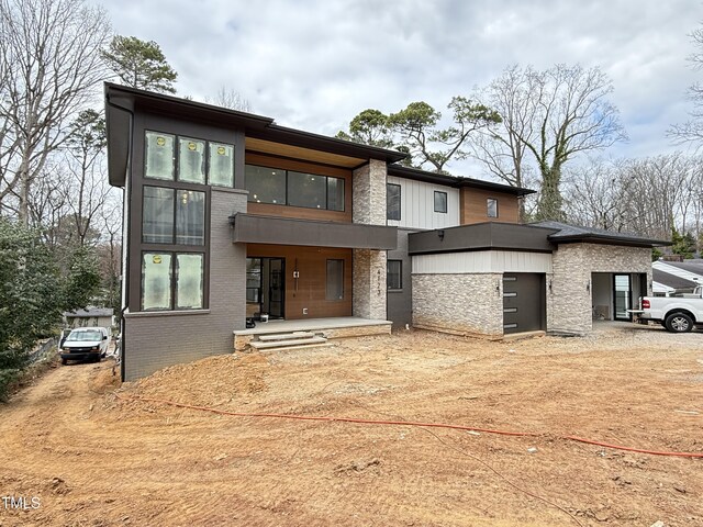 contemporary house featuring stone siding and driveway