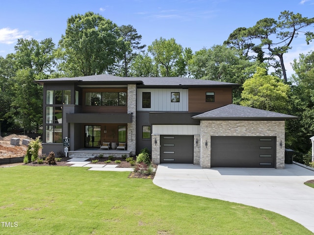 4123 Rockingham Dr, Raleigh, NC 27609 - contemporary house featuring driveway, a front yard, stone siding, a garage, and covered porch
