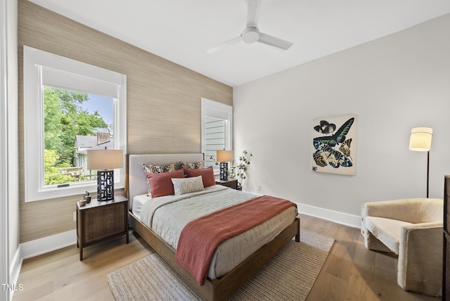 4123 Rockingham Dr, Raleigh, NC 27609 - bedroom featuring wallpapered walls, baseboards, an accent wall, light wood-type flooring, and ceiling fan