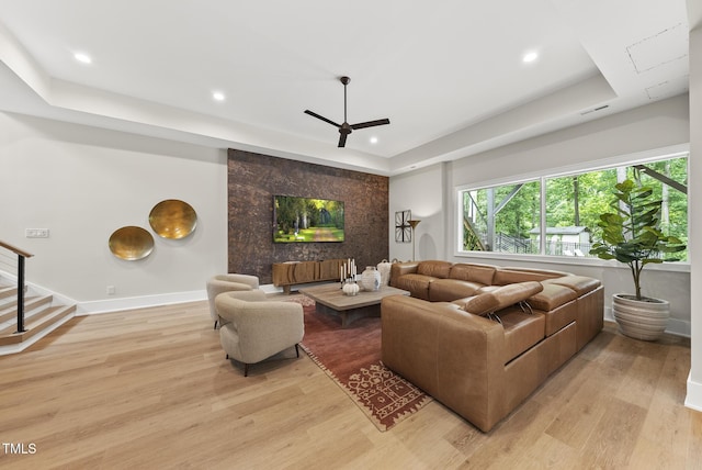 4123 Rockingham Dr, Raleigh, NC 27609 - living room featuring a tray ceiling, ceiling fan, light wood-style floors, stairway, and baseboards