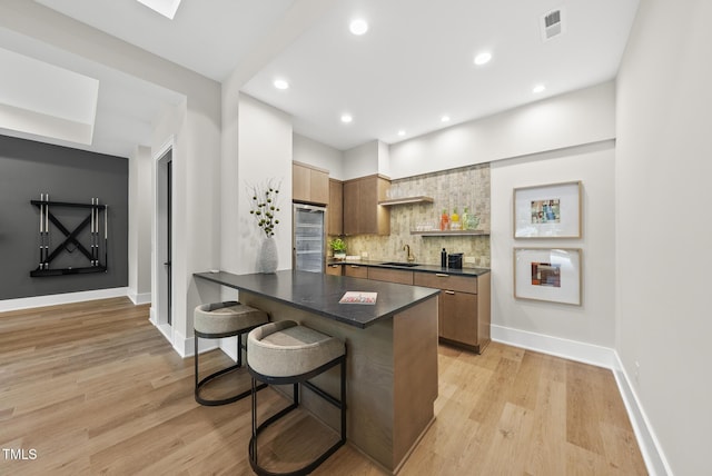 4123 Rockingham Dr, Raleigh, NC 27609 - kitchen featuring dark countertops, a sink, backsplash, a kitchen breakfast bar, and a peninsula