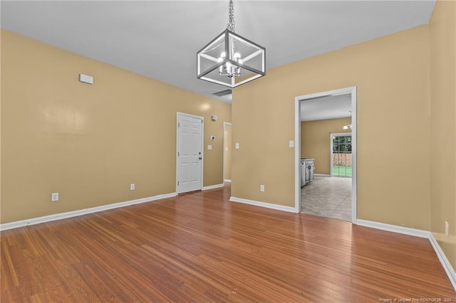 spare room featuring hardwood / wood-style flooring and a notable chandelier