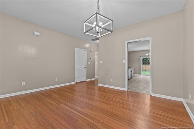 spare room with an inviting chandelier and light wood-type flooring