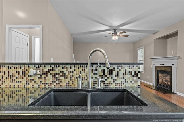 kitchen featuring decorative backsplash, dark stone counters, hardwood / wood-style flooring, and sink