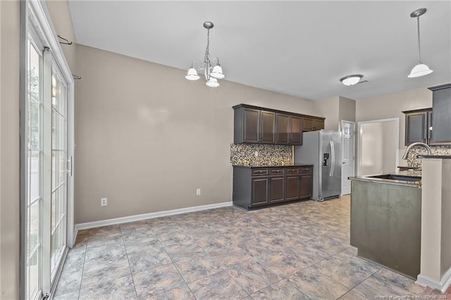 kitchen featuring decorative backsplash, decorative light fixtures, stainless steel refrigerator with ice dispenser, and sink