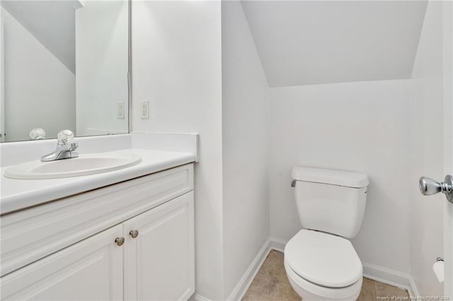 bathroom with lofted ceiling, tile patterned floors, vanity, and toilet