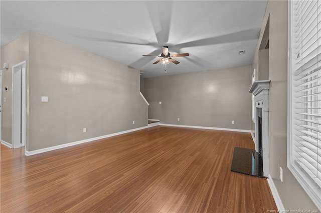 60 Hunters Way, Angier, NC 27501 - unfurnished living room with baseboards, wood finished floors, a ceiling fan, and a fireplace with flush hearth