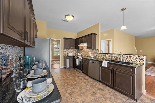 60 Hunters Way, Angier, NC 27501 - kitchen with appliances with stainless steel finishes, under cabinet range hood, dark brown cabinets, a peninsula, and tasteful backsplash