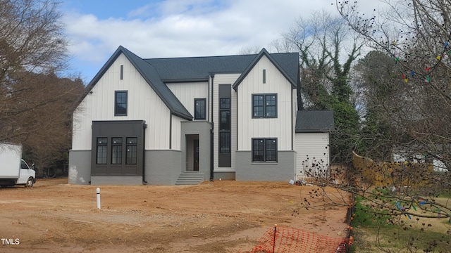 modern farmhouse with entry steps, board and batten siding, brick siding, and roof with shingles