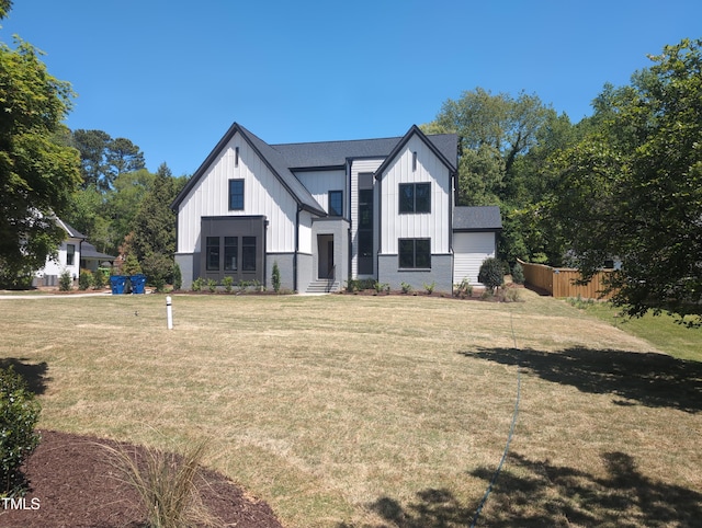back of house featuring board and batten siding, a lawn, and fence