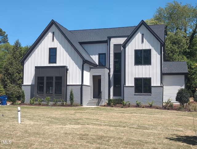 view of front of house featuring board and batten siding, a shingled roof, a front lawn, and brick siding