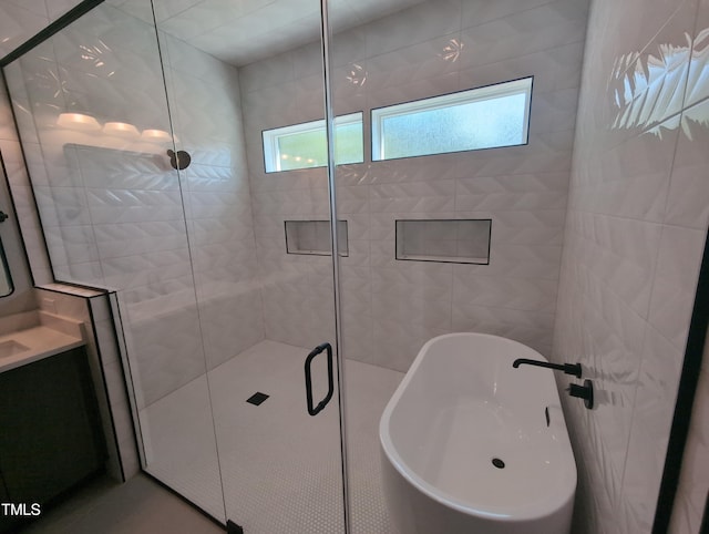 bathroom with a freestanding bath, a shower stall, and vanity