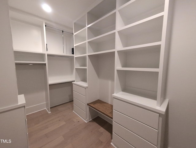 walk in closet featuring built in desk and light wood-style floors