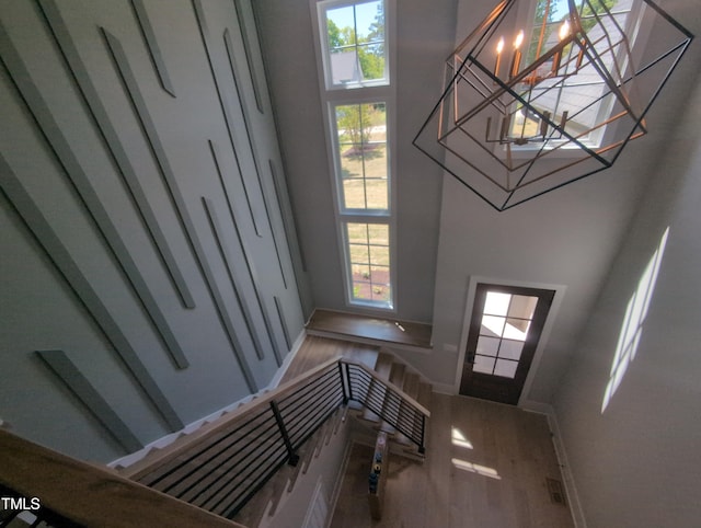 foyer entrance featuring a notable chandelier, baseboards, a towering ceiling, and wood finished floors