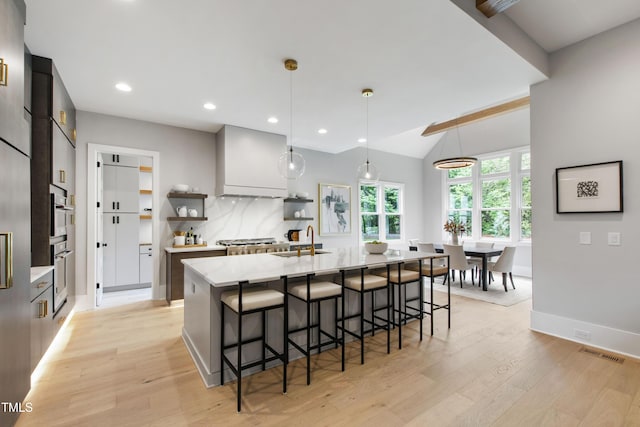 5812 Shawood Dr, Raleigh, NC 27609 - kitchen featuring open shelves, a sink, light wood finished floors, a breakfast bar, and recessed lighting